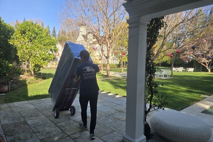 Movers carrying wrapped furniture down outdoor stairs